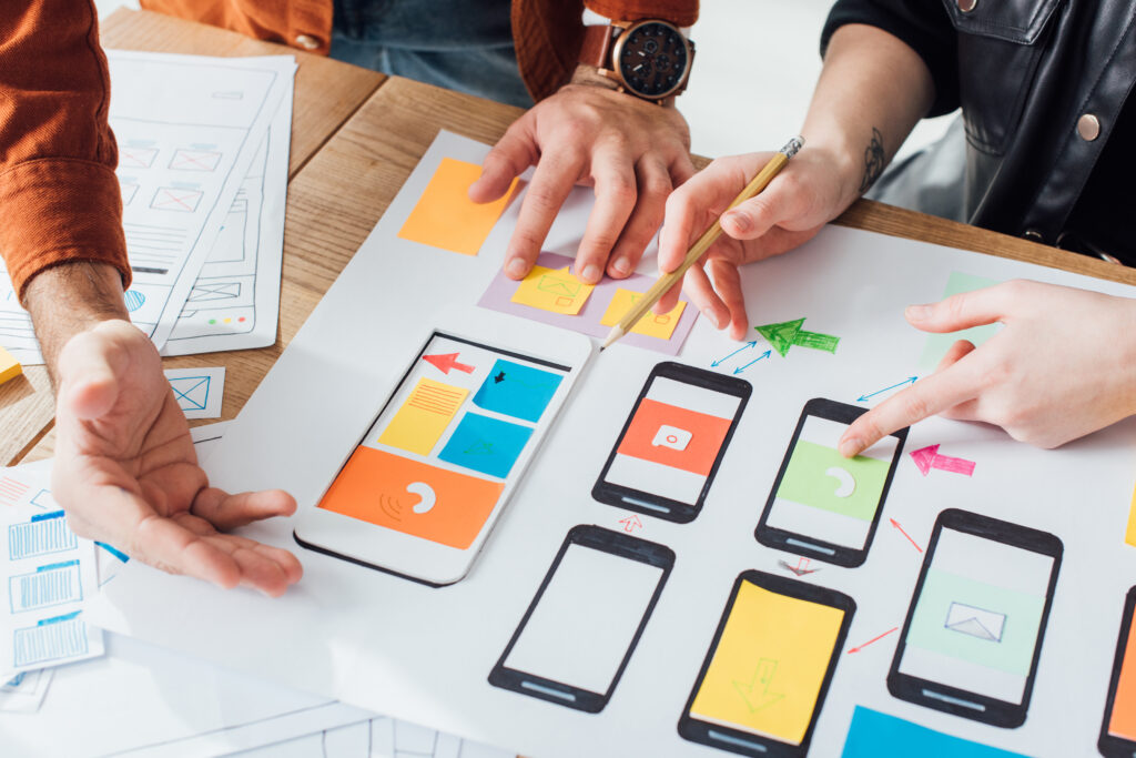Cropped view of developers creative user experience design of mobile website with layouts on table